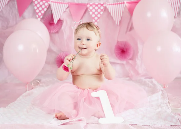 Portrait of cute adorable Caucasian baby girl with blue eyes in pink tutu skirt celebrate his first birthday with gourmet cake and balloons looking away, cake smash first year concept — Stok Foto