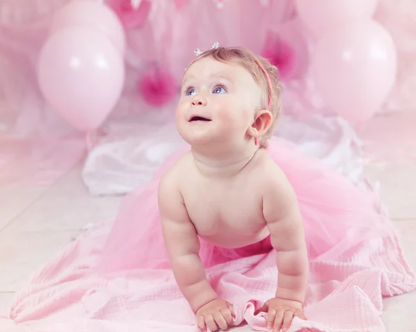 Portret van leuk schattig Kaukasische babymeisje met blauwe ogen in roze tutu rok viert haar eerste verjaardag met gastronomische taart en ballonnen op zoek weg, cake smash eerste jaar concept — Stockfoto