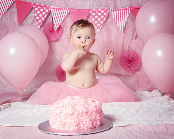 Retrato de bonito adorável menina caucasiana com olhos azuis em saia de tutu rosa comemorando seu primeiro aniversário com bolo gourmet e balões olhando na câmera, conceito de primeiro ano bolo smash — Fotografia de Stock
