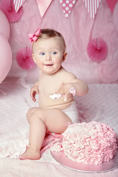 Portrait of cute adorable Caucasian baby girl with blue eyes in pink tutu skirt celebrate his first birthday with gourmet cake and balloons looking away, cake smash first year concept — Stok Foto