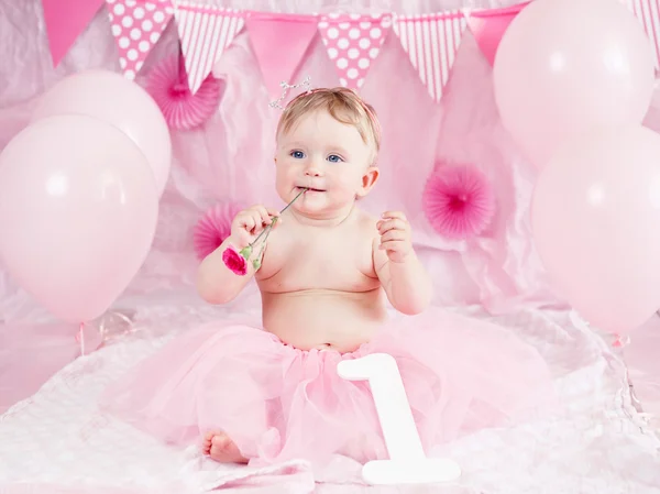Portrait of cute adorable Caucasian baby girl with blue eyes in pink tutu skirt celebrate his first birthday with flower, gourmet cake and balloons looking away, cake smash first year concept — Stok Foto