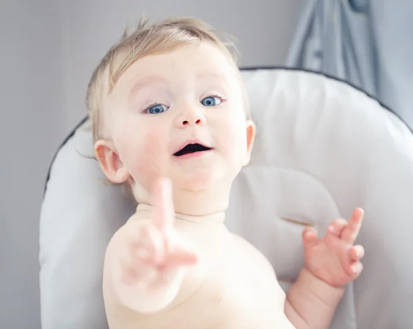 Portret zbliżenie ładny śliczny śmieszne Kaukaska uśmiechający się roześmiany baby chłopiec blondynka z niebieskie oczy, twarz wyrażenie pokazuje palcem — Zdjęcie stockowe