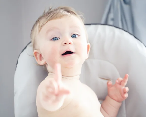 Primer plano retrato de linda adorable divertida rubia caucásica sonriente niña niño riendo con ojos azules con expresión emocional de la cara que muestra un dedo —  Fotos de Stock