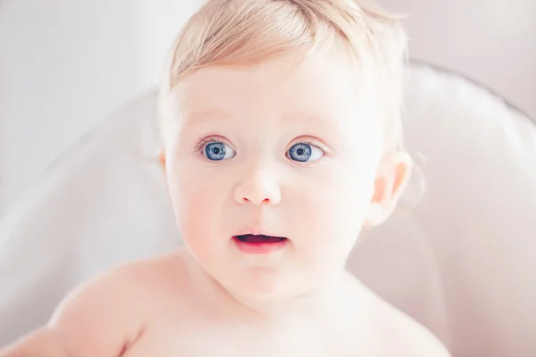 Closeup retrato de bonito adorável engraçado loira caucasiano sorrindo rindo bebê menina com olhos azuis com expressão facial emocional sentado em cadeira alta na cozinha olhando para longe — Fotografia de Stock