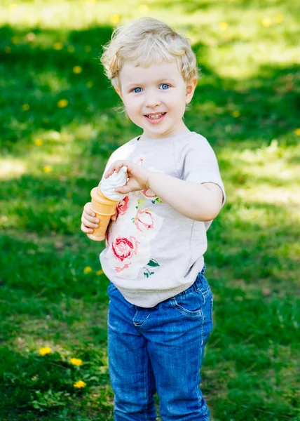 Porträt des niedlichen lustigen kleinen blonden kaukasischen Mädchens Kleinkind, das in der grünen Waldwiese steht und Seifenblasen bläst, heller Sommertag, Sommerspaß — Stockfoto