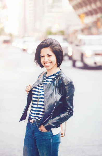 Retrato de belo sorriso jovem caucasiano latino menina mulher com olhos castanhos escuros e cabelo escuro curto em jeans azul, jaqueta de couro motociclista na rua da cidade, tonificado com filtros Instagram — Fotografia de Stock