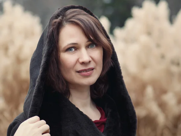 Primer plano retrato de hermosa mujer morena blanca caucásica de mediana edad con ojos verdes en chaqueta de abrigo en otoño día de otoño fuera mirando en cámara sobre fondo de centeno amarillo — Foto de Stock