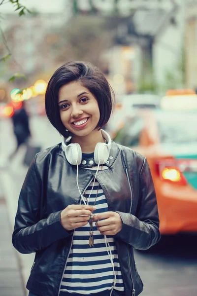 Retrato de hermosa mujer latina hispana pelo corto y negro en chaqueta de cuero con auriculares afuera en la noche noche calle de la ciudad sonriendo mirando en cámara, estilo de vida concepto de retrato —  Fotos de Stock