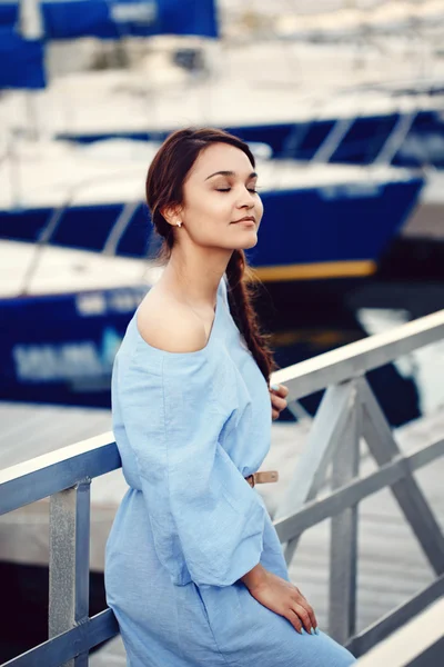 Retrato de mulher branca morena caucasiana com pele bronzeada em vestido azul à beira-mar lakeshore com iates barcos no fundo na água, conceito de estilo de vida — Fotografia de Stock