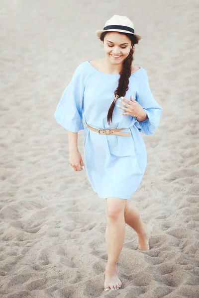 Portrait of smiling laughing white Caucasian brunette woman with tanned skin in blue dress and straw hat running on sand beach, sunset on summer day, lifestyle concept — Stock Photo, Image