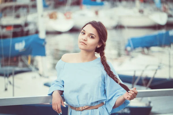 Portrét bílé bruneta běloška s opálenou pletí v modrých šatech od pobřeží jezera s čluny jachty na pozadí na vodě, životní styl koncepce — Stock fotografie