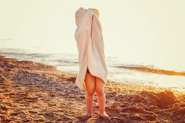 Retrato de lindo adorable niño pequeño feliz niña con toalla de playa ocultándose cubriendo divertirse, estilo de vida atardecer humor de verano, tonificado con filtros de Instagram —  Fotos de Stock