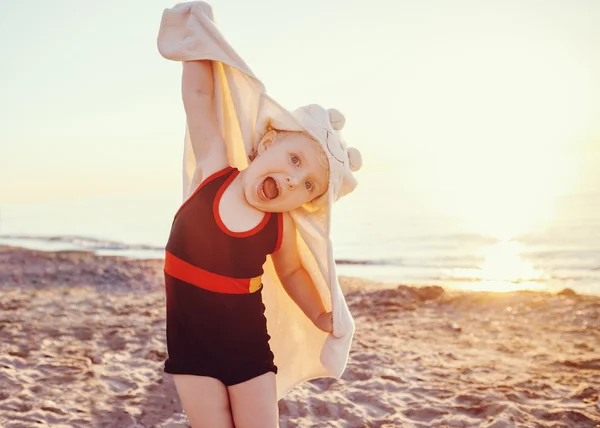 Potret gadis kecil lucu yang sedang tersenyum dengan senyuman manis dengan handuk di pantai berpose wajah gembira, ekspresi wajah emosional, suasana hati musim panas gaya hidup, kencang — Stok Foto