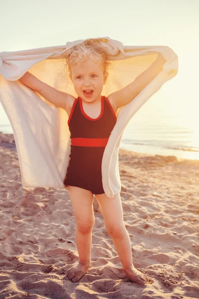 Potret gadis kecil lucu yang sedang tersenyum dengan senyuman manis dengan handuk di pantai berpose wajah gembira, ekspresi wajah emosional, suasana hati musim panas gaya hidup, kencang — Stok Foto