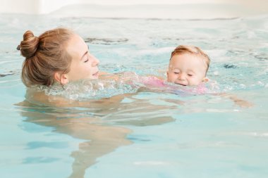 Beyaz Beyaz Beyaz anne ve bebek kızı nın yüzme havuzunda su dalışı oynarken, yüzme eğitimi, sağlıklı aktif yaşam tarzı grup portresi