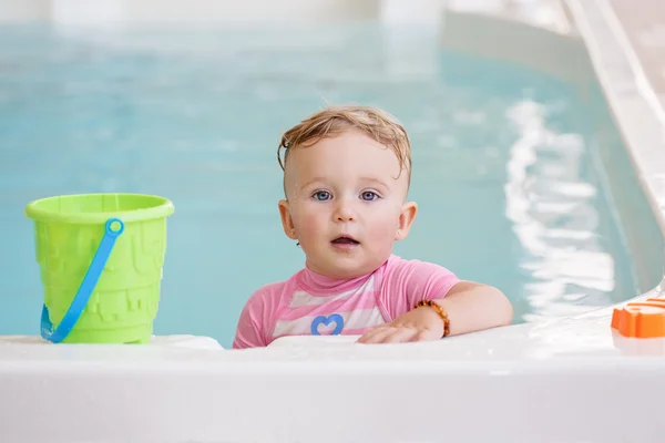 Retrato de branco caucasiano bebê menina brincando com brinquedos na água em pé à beira da piscina nariz dentro, olhando para a câmera, treinamento para nadar, estilo de vida ativo saudável — Fotografia de Stock