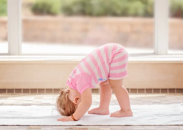 Portrait of cute adorable white Caucasian baby girl doing physical fitness exercise yoga alone standing on floor in swimming pool — Stok Foto