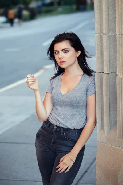 Portrait de blanche Caucasienne belle jeune femme brune adolescente en jeans et t-shirt à l'extérieur dans la ville urbaine sur le coucher du soleil fumer cigarette regarder à la caméra, tonique avec des filtres Instagram — Photo