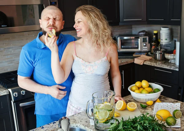 Portrait of smiling laughing white Caucasian couple two people pregnant woman with husband cooking food, eating citrus juice in kitchen, lifestyle healthy pregnancy happy life concept