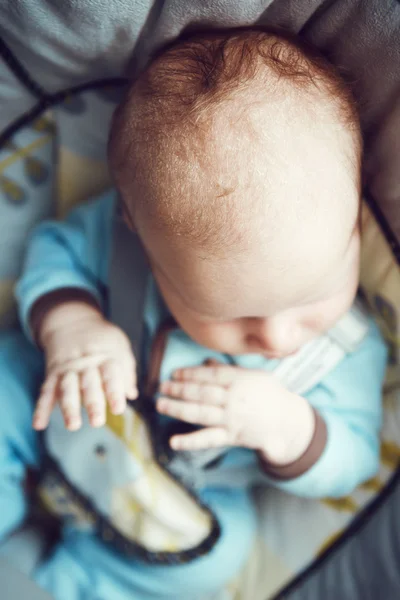 Potret lucu lucu putih Kaukasia tidur bayi laki-laki kecil yang baru lahir dengan pakaian biru duduk di kursi ayunan, pandangan kepala tangannya dari atas, posisi embrio janin — Stok Foto