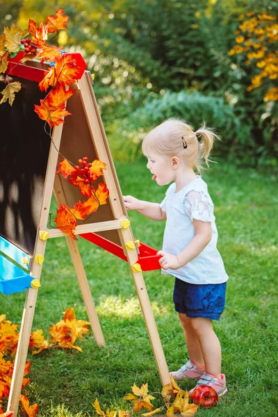 Vit kaukasiska småbarn barn kid flicka stå utomhus på sommaren hösten park ritning på staffli med markörer tittar bort, spelar studerar lärande, tillbaka till skolan — Stockfoto