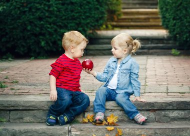 Group portrait of two white Caucasian cute adorable funny children toddlers sitting together sharing apple food, love friendship childhood concept, best friends forever clipart