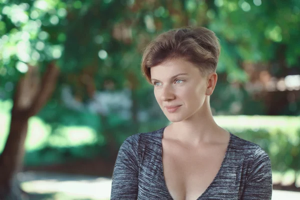 Retrato de sonriente joven de mediana edad blanca caucásica chica mujer con pelo corto corte de pelo elegante en la camiseta mirando hacia fuera en el parque de verano, estilo de vida de moda de belleza — Foto de Stock