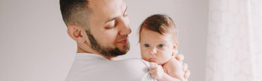 Babam yeni doğmuş bebeği omuzlarında taşıyor. Erkek ebeveyn, çocuğunu kucağında tutuyor. Otantik aile yaşam tarzı belgesel anı. Babalar Günü tatili. Web başlığı.