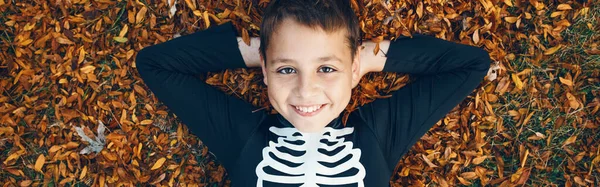 Хэллоуин Счастливый Мальчик Костюме Скелета Лежит Куче Желтых Листьев Открытом — стоковое фото