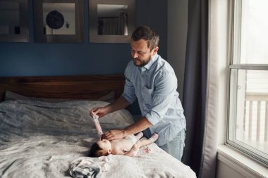Orta yaşlı, beyaz bir baba, yeni doğan kız çocuğu için bebek bezi değiştiriyor. Erkek ebeveyn, çocuğuna evde bakıyor. Otantik yaşam tarzı samimi anı. Bekar baba aile hayatı. Babalar Günü.