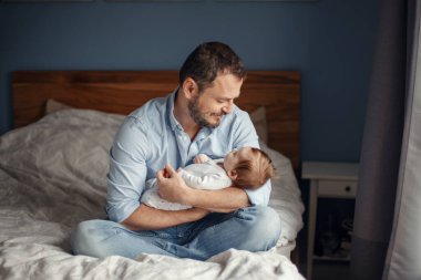 Babalar Günü. Orta yaşlı beyaz bir baba ve uyuyan yeni doğmuş bir kız bebek. Çocuğunu kucağında tutan bir ebeveyn. Otantik ebeveynlik anı. Bekar baba aile hayatı..