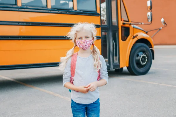 Χαρούμενη Λευκή Μαθήτρια Μάσκα Προσώπου Κοντά Στο Κίτρινο Λεωφορείο Παιδί — Φωτογραφία Αρχείου