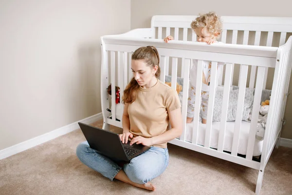 家庭からラップトップで働いている赤ちゃんを持つ白人の母親 子供の幼児とのフリーランスのビジネス女性の職場 ビデオチャットコール 家にいるシングルマザー稼ぐお金で遠い仕事でオンライン — ストック写真