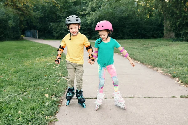 Happy Caucasian Friends Boy Girl Helmets Riding Roller Skates Park Royalty Free Stock Images