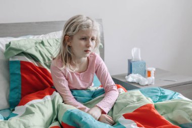 Ateşli, hasta, beyaz bir kız yatağında yatıyor. Virüs grip mevsimi hastalığı. Tıp ve sağlık konsepti. Hasta, üzgün, mutsuz bir çocuk evde oturup ateş hastalığına yakalandı..