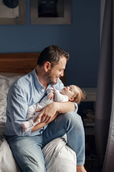 Fathers Day holiday. Middle age Caucasian father with sleeping newborn baby girl. Parent holding rocking child daughter son in hands arms. Authentic lifestyle parenting fatherhood moments.