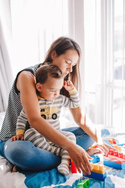 Mother and baby toddler playing learning toy stacking building blocks at home. Early age Montessori education. Kids hand brain and fine motor skills development. Logic activity for preschoolers.