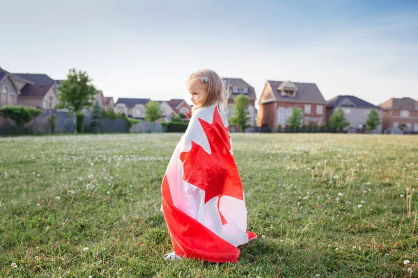 กทารกหญ วเล วยธงแคนาดาขนาดใหญ นในสวนสนามหญ ากลางแจ งานฉลองว นแคนาดาข างนอก ปกคล วยธงแคนาดาเฉล — ภาพถ่ายสต็อก