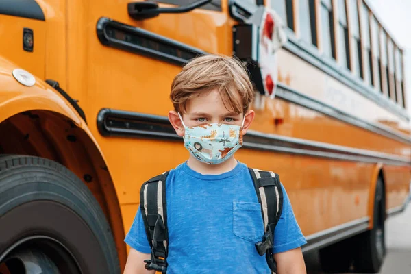 校外の黄色いバスの近くの保護面の男の子の子供の学生 コロナウイルスCovid 19パンデミックにおける新たな正常性 授業中に広がるウイルス対策 — ストック写真