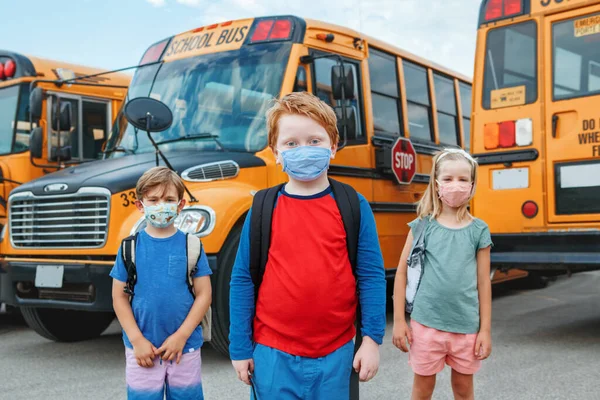 Tres Niños Estudiantes Máscaras Protectoras Cerca Del Autobús Amarillo Escolar — Foto de Stock