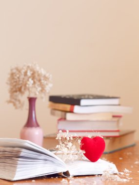 Sedilmiş çiçeklerle kitap yığını