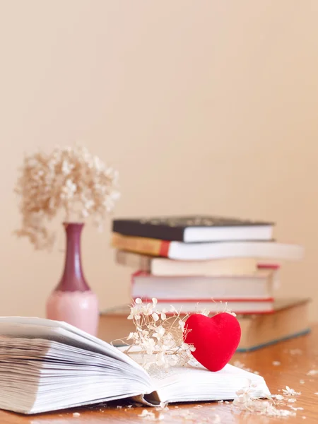 Sedilmiş çiçeklerle kitap yığını