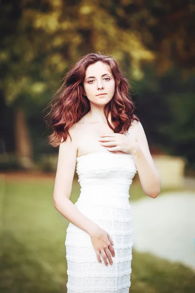 Innocent beautiful girl in white dress in park