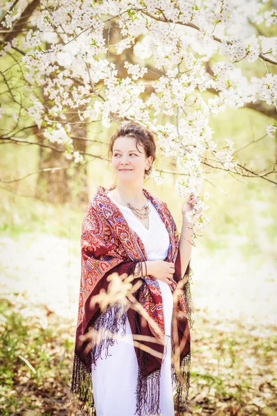 Беременная женщина в парке среди цветущих деревьев весной — стоковое фото