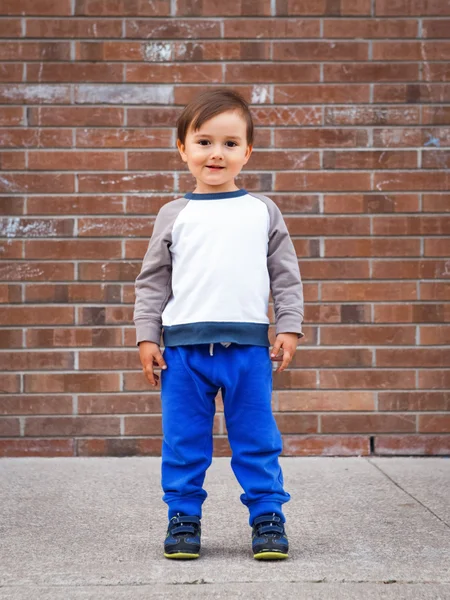 Tuğla duvar gülüyor tarafından yürümeye başlayan çocuk — Stok fotoğraf