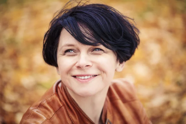 Brunette middle aged woman outside in autumn park Stock Photo