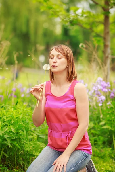 Young girl blowing dandelions — Stock Photo, Image