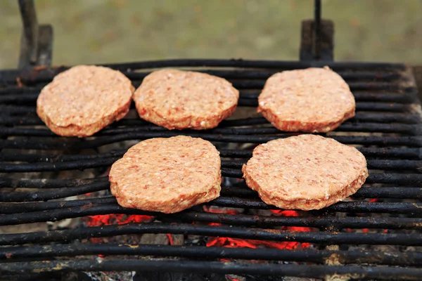 Fem rått kött grill hamburgare på grillen — Stockfoto