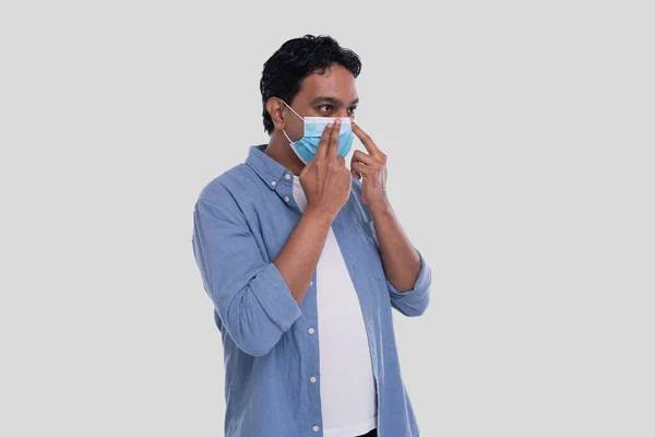 Indian Man sätter på Medical Mask Isolerad. Man i blå tröja visar hur man tar på sig medicinsk mask. Hälsa, virus, medicinskt begrepp — Stockfoto