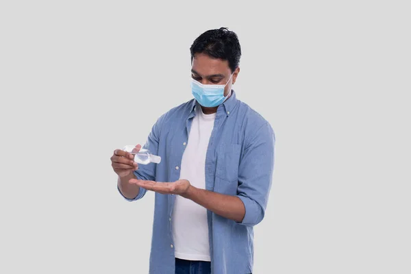Indian Man bär medicinsk mask med hjälp av handdesinfektionsmedel. Man som använder händerna antiseptiska — Stockfoto